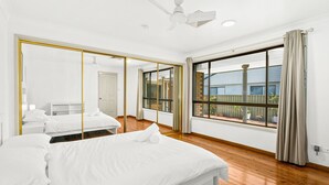 Une chambre d’hôtel moderne dotée d’un grand miroir, d’un lit, d’un ventilateur de plafond et offrant une vue sur l’extérieur.