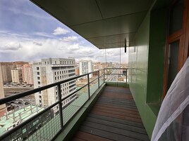 Uma varanda com vista para a paisagem urbana, incluindo edifícios e um parque de estacionamento.