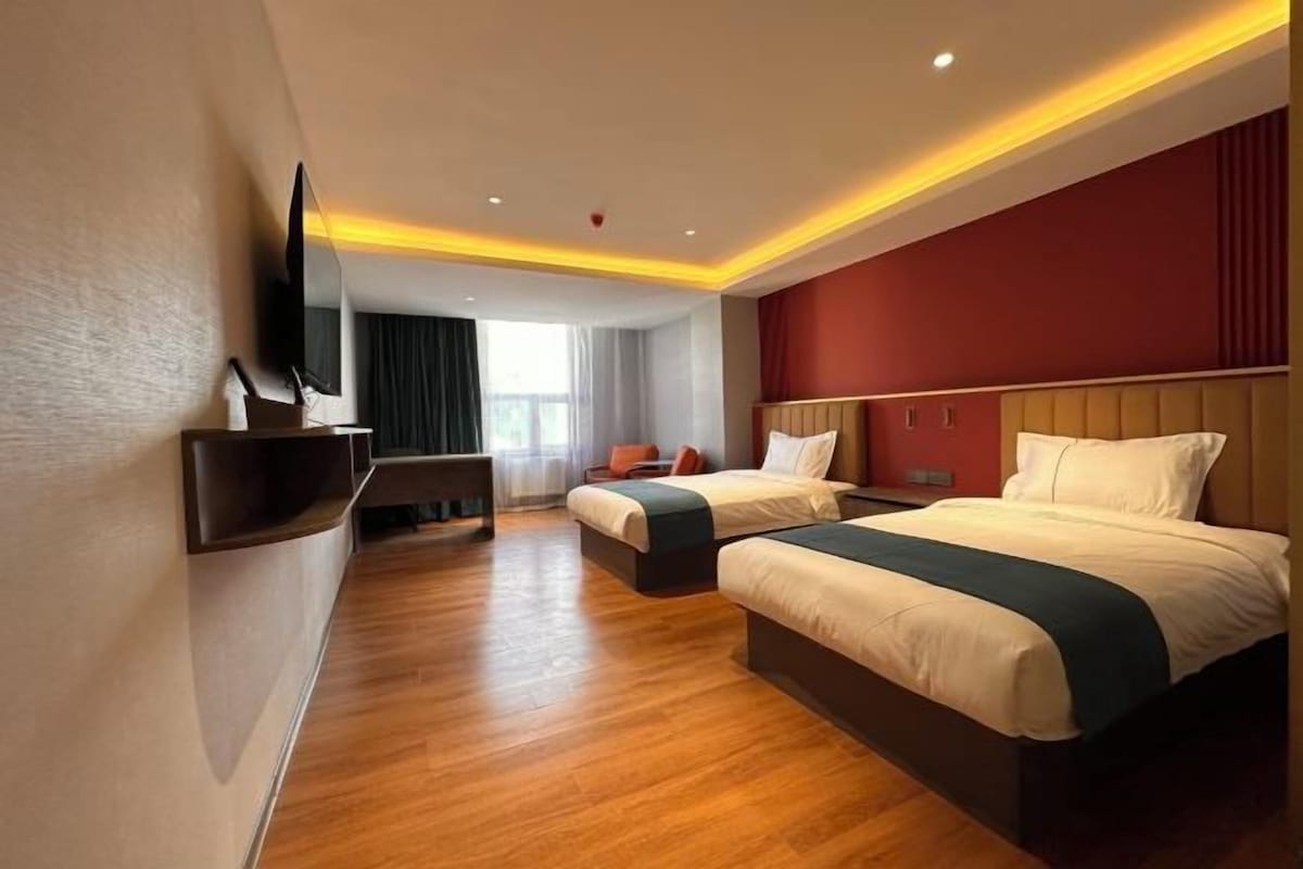 Une chambre d’hôtel avec deux lits, un téléviseur fixé au mur et un bureau avec une chaise.