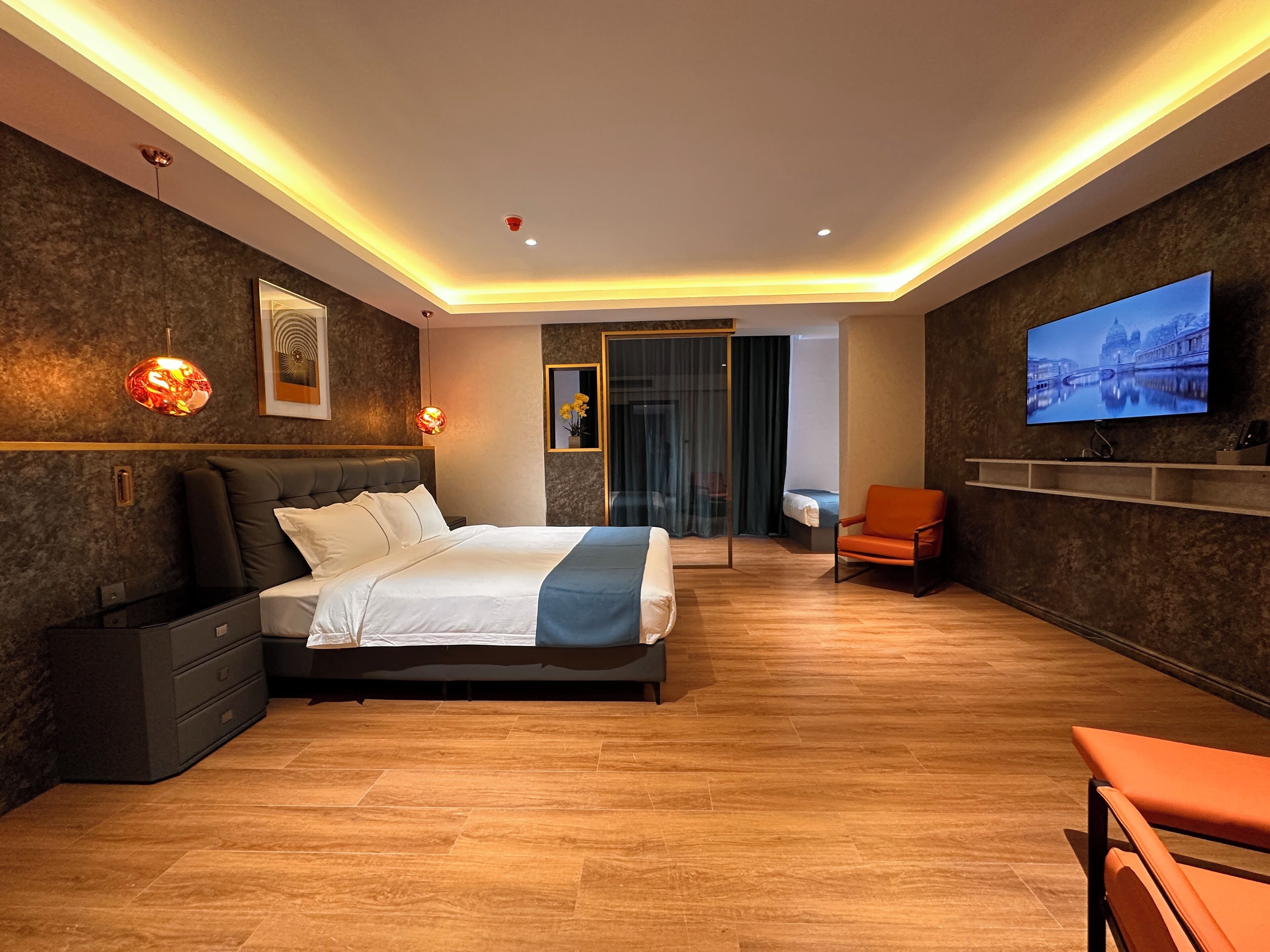 A modern hotel room with a large bed, a TV, a desk, and a chair.