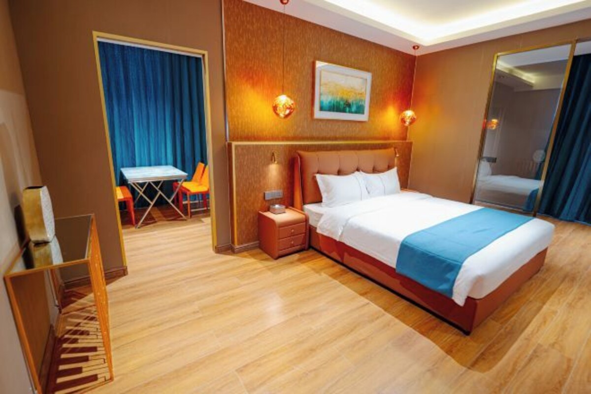 A hotel room with a large bed, a desk, and a chair.