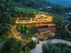 A multi-story building with a rustic design, surrounded by lush greenery and terraced fields. - Ta Phin Cottage (Ta Phin)