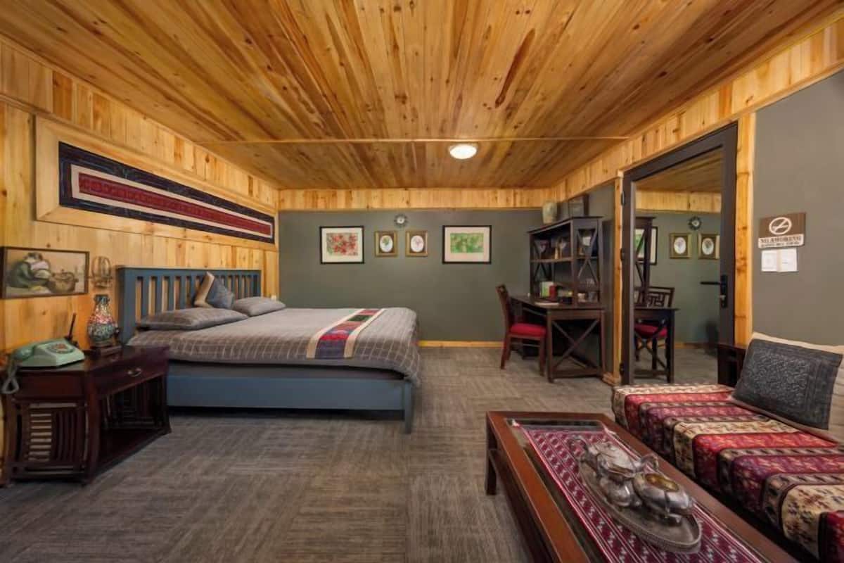 A room with a bed, a desk, a chair, and a sofa.