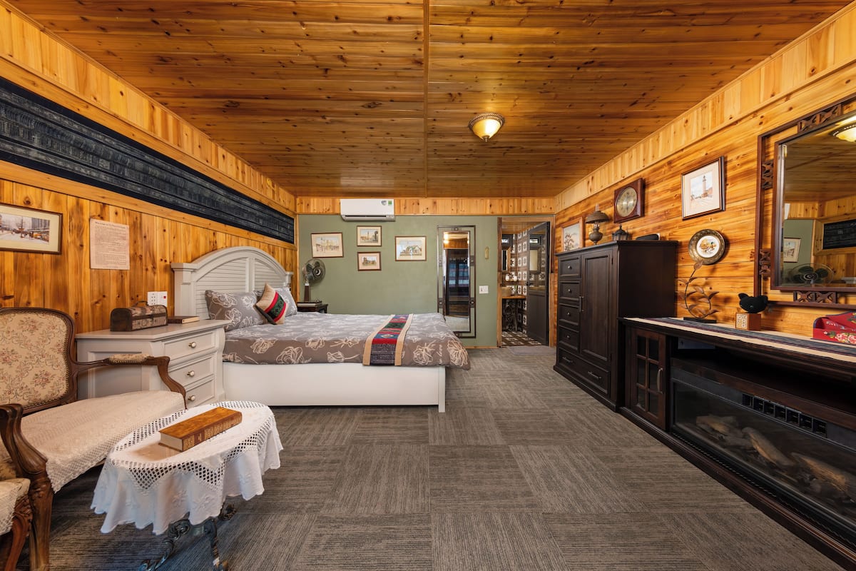 A cozy room with a bed, dresser, and a fireplace.
