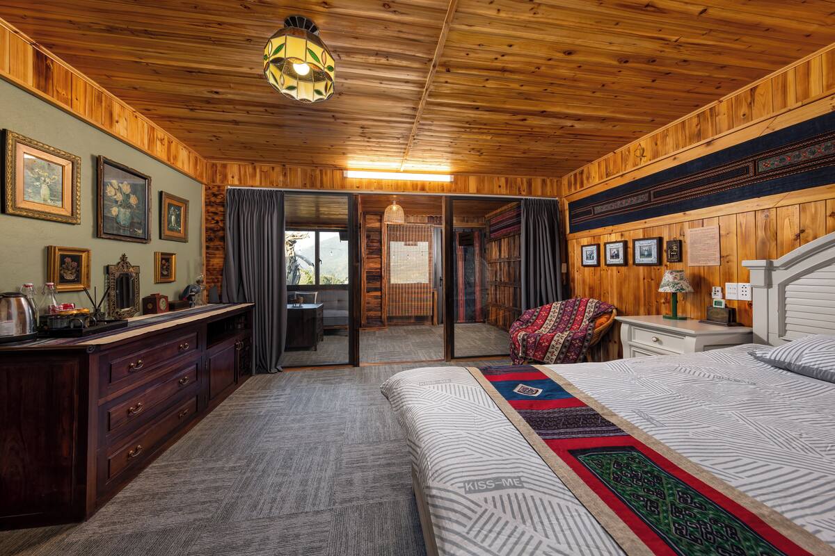 A wooden-paneled bedroom with a large bed, a dresser, and a desk.