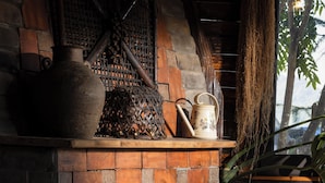A rustic fireplace with a brick design, a decorative vase, and a hanging plant.