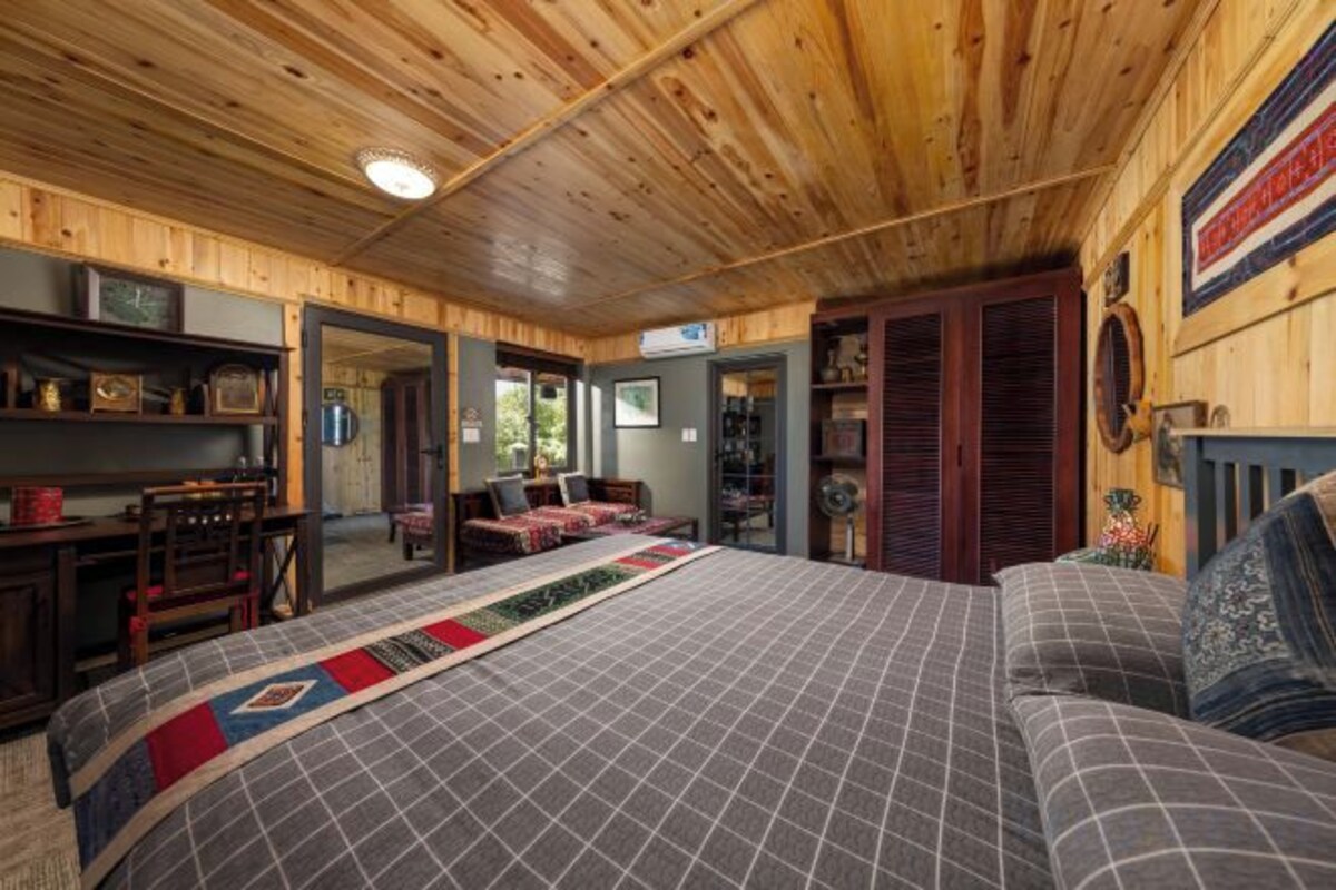 Una habitación con paneles de madera, una cama, un sofá, un escritorio y una chimenea.