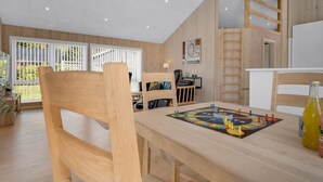 A spacious room with a wooden table, chairs, and a board game. There is a window with blinds, a staircase, and a door. - "Ebertine" - 740m to the fjord by Interhome (Storvorde)