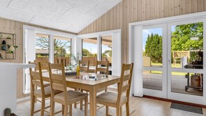 A dining area with a wooden table and chairs, large windows, and a view of the outdoors. - "Ebertine" - 740m to the fjord by Interhome (Storvorde)
