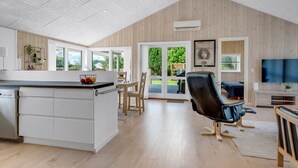 A spacious kitchen with a central island, a dining area with wooden chairs, a large window, and a flat-screen TV mounted on the wall. - "Ebertine" - 740m to the fjord by Interhome (Storvorde)