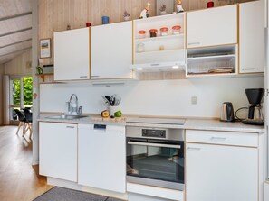 A modern kitchen with white cabinetry, a built-in oven, and a coffee maker.