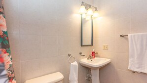 A bathroom with a toilet, sink, and shower with three lights. - 2-bedroom condo in West End at Sunset Villas with WiFi, AC and Ocean View (Roatan)