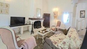 A living room with a fireplace, a television, a sofa, and a chandelier. - Charming house near Bergerac with private garden (Ginestet)