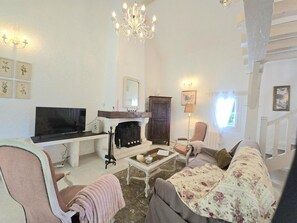 A living room with a fireplace, a television, a sofa, and a chandelier.
