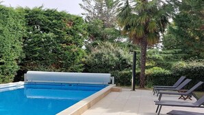Une piscine couverte, entourée de chaises longues et d’une végétation luxuriante.