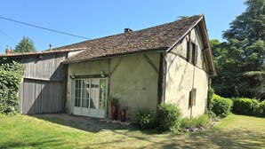 A rustic two-story house with a sloped roof, a front door with glass panels, and a small garden area with potted plants. - Charming house near Bergerac with private garden (Ginestet)