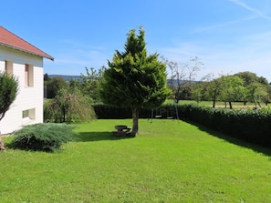 A grassy yard with a tree, a bench, and a white building with a red roof. - Charming 4* Cottage in a Peaceful Vosges Hamlet (Fougerolles-Saint-Valbert)
