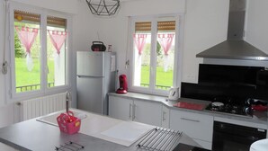 A modern kitchen with a refrigerator, stove, and kettle.