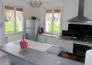 A modern kitchen with a refrigerator, stove, and kettle.