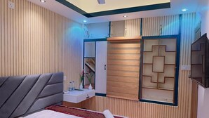 Une chambre à coucher moderne comprenant un lit, une coiffeuse, une armoire, un ventilateur de plafond et un téléviseur.