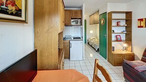 A compact living space with a kitchenette, a dining area, and a bedroom. - Bright studio with balcony, pets allowed (Lamalou-les-Bains)