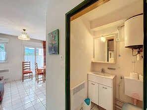 Quarto de hotel com banheiro, área de refeições com mesa e cadeiras, e vista para o exterior.