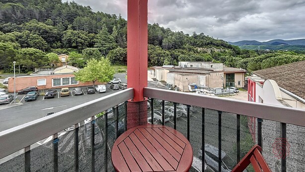 A balcony with a view of a parking lot, buildings, and a forested hillside. - Bright studio with balcony, pets allowed (Lamalou-les-Bains)