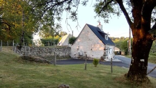 A stone building with a sloped roof, surrounded by a stone wall and a fenced area. - Charming House in Cros - 3 pers, Volcano Park (Cros)
