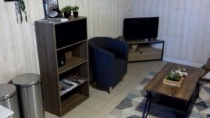 A living room with a sofa, a coffee table, a TV, and a bookshelf. - Charming House in Cros - 3 pers, Volcano Park (Cros)