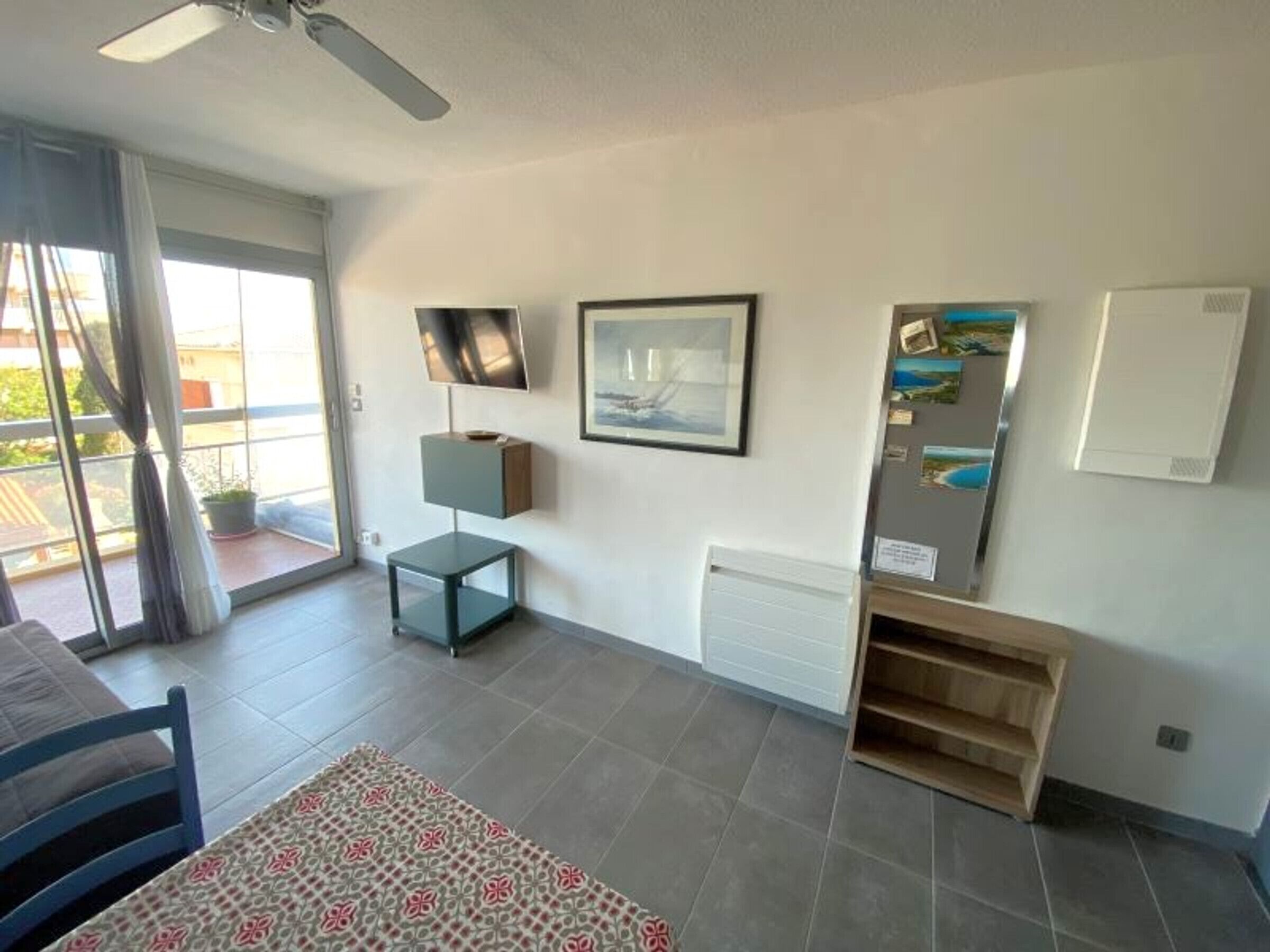 A modern living room with a flat-screen TV, a framed picture, a small table, and a built-in shelving unit.