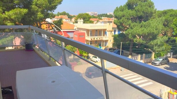 A balcony with a table and chairs, overlooking a street with cars and buildings. - Beachfront apartment for 4 with parking (Argelès-sur-Mer)