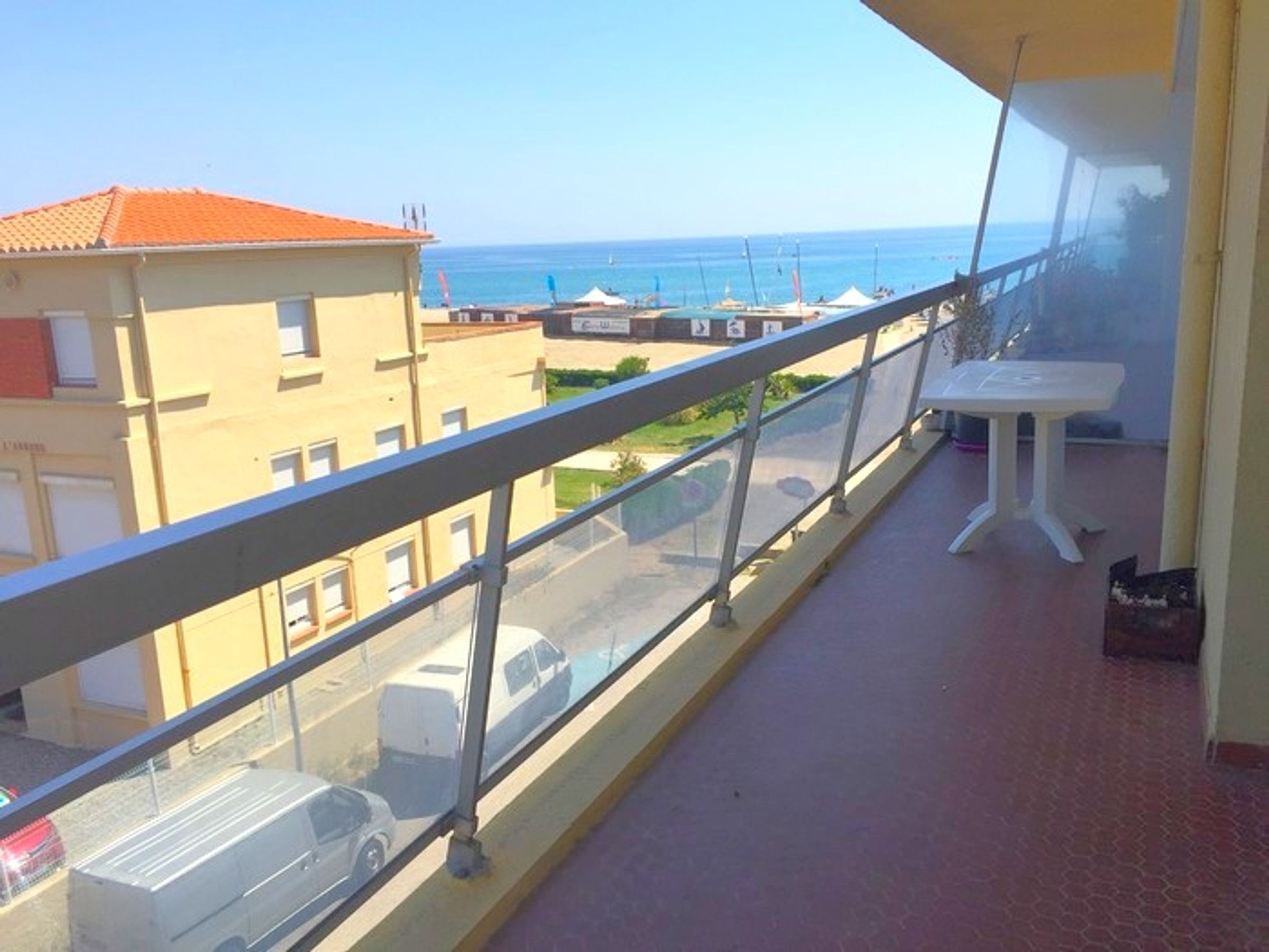 Un balcon avec vue sur la mer, une table et une rambarde.