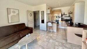 A modern living room with a brown sofa, a coffee table, and a dining area with a small table and chairs. - 2-room apartment in Porticcio with air conditioning and parking (Porticcio)