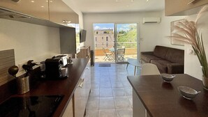 A modern kitchen with a dining area, a sliding glass door leading to an outdoor patio, and a view of the surrounding buildings. - 2-room apartment in Porticcio with air conditioning and parking (Porticcio)