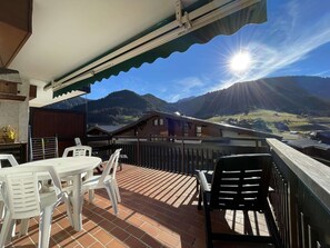 A terrace with a table and chairs, a view of mountains, and a sunny sky. - Studio cabin in Praz-sur-Arly near slopes with parking (Praz-sur-Arly)