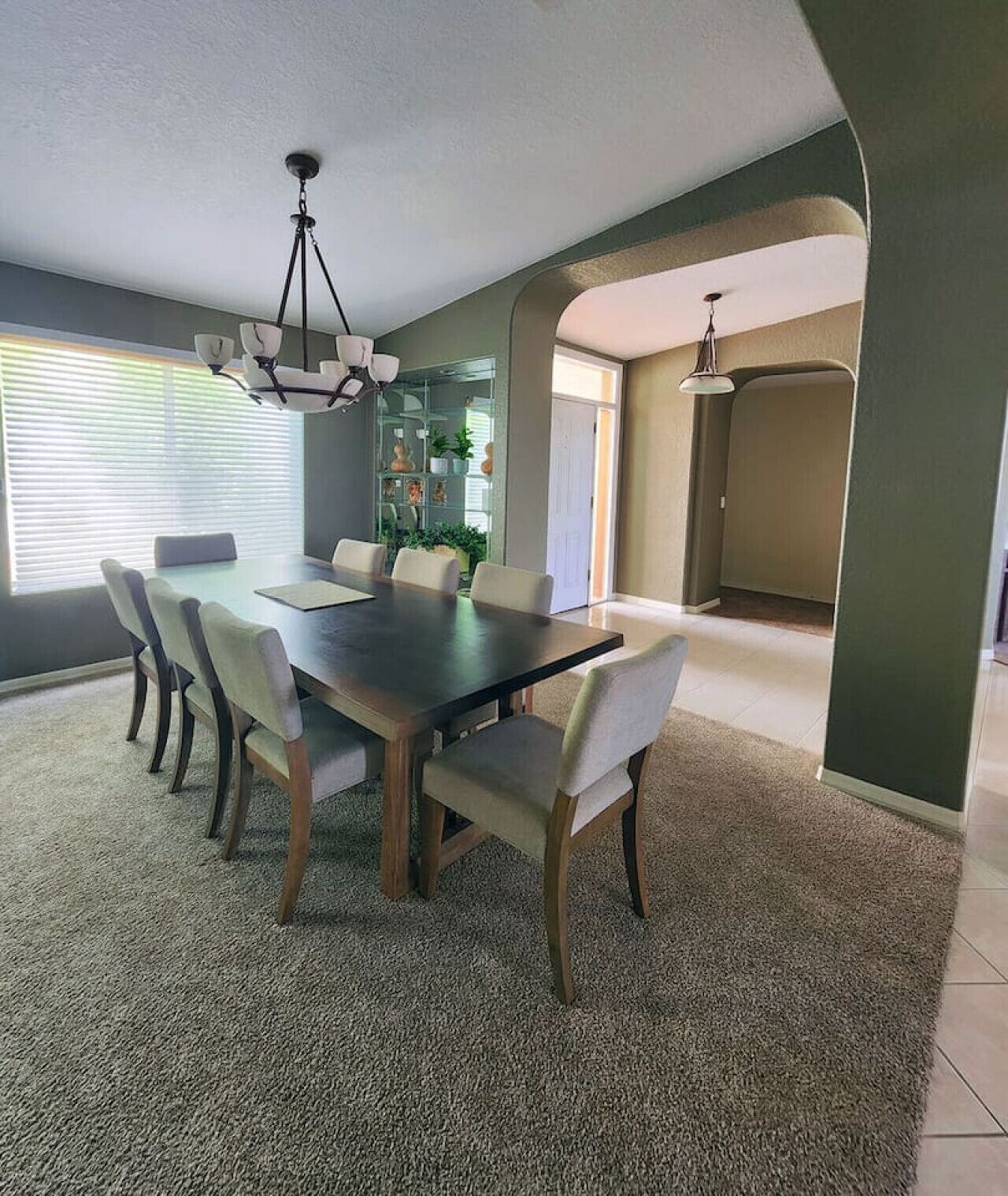 Un coin repas avec une table en bois foncé, six chaises et un lustre.