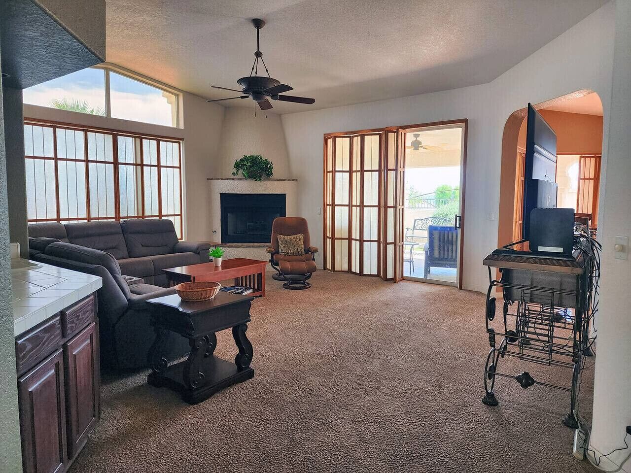 A living room with a sofa, a coffee table, a fireplace, a television, and a sliding glass door leading to an outdoor area.