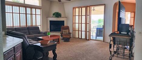 A living room with a sofa, a coffee table, a fireplace, a television, and a sliding glass door leading to an outdoor area.