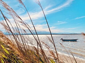 A boat on a calm body of water with a clear sky and distant mountains. - Le Sea View - 3-Bedroom Apartment - Ocean View - Terrace - Parking. (Canet-en-Roussillon)