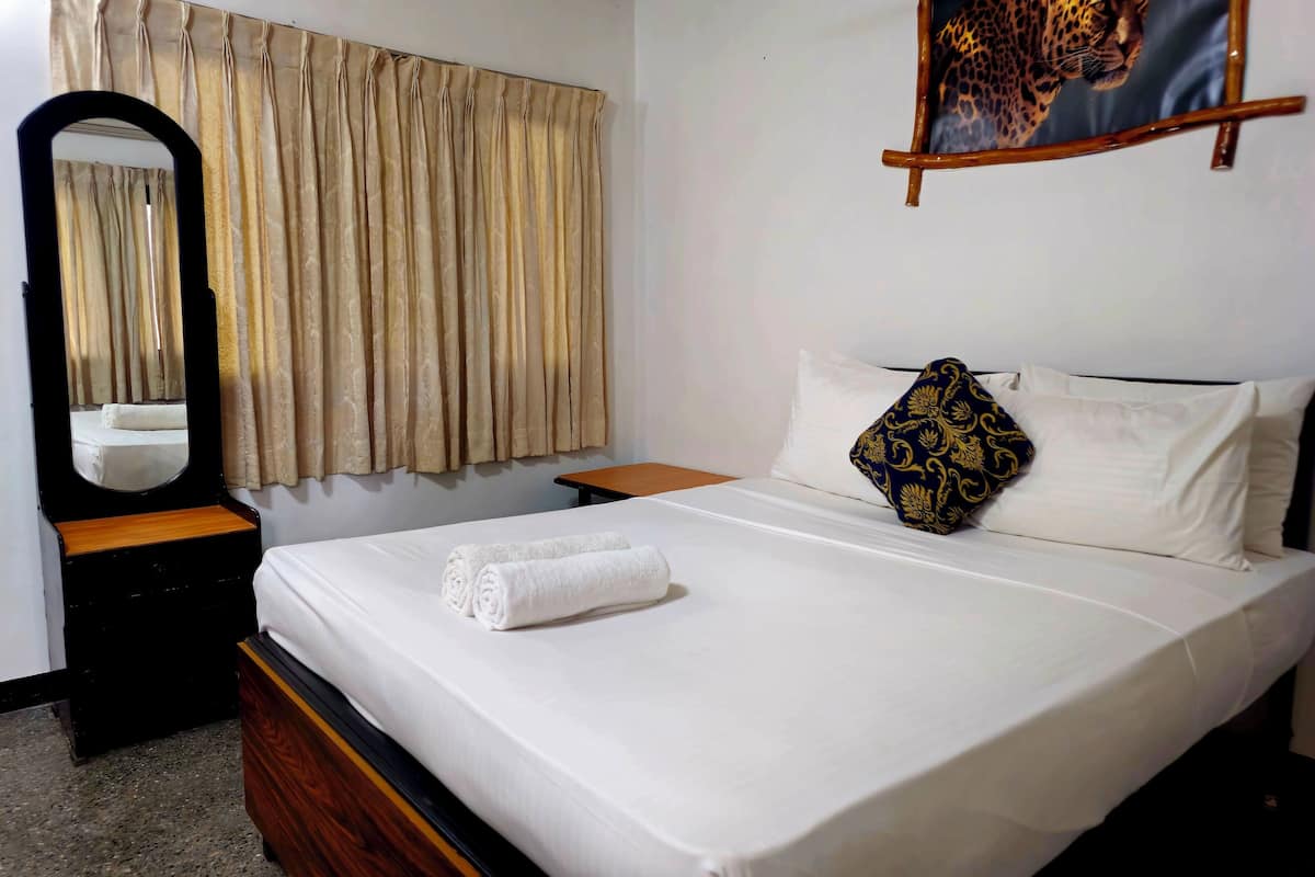 Una cama bien hecha con sábanas blancas, un cabecero de madera y una almohada decorativa.