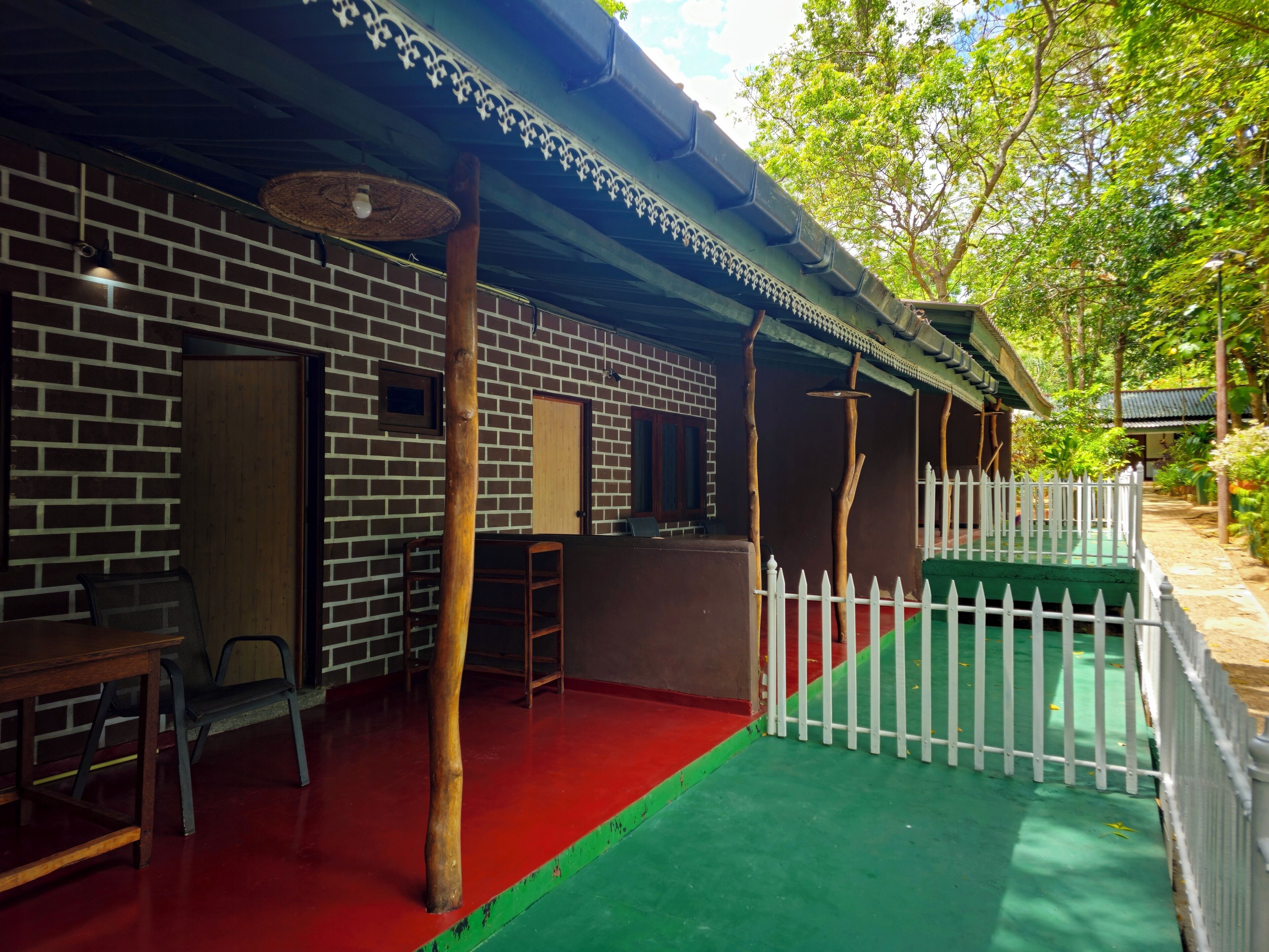 A brick building with a red floor, a white picket fence, and a green area.