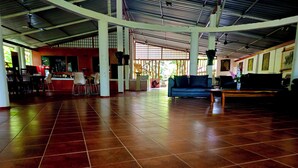 A spacious indoor area with a tiled floor, a blue sofa, and a wooden table. - Safari Village Hotel (Udawalawa)