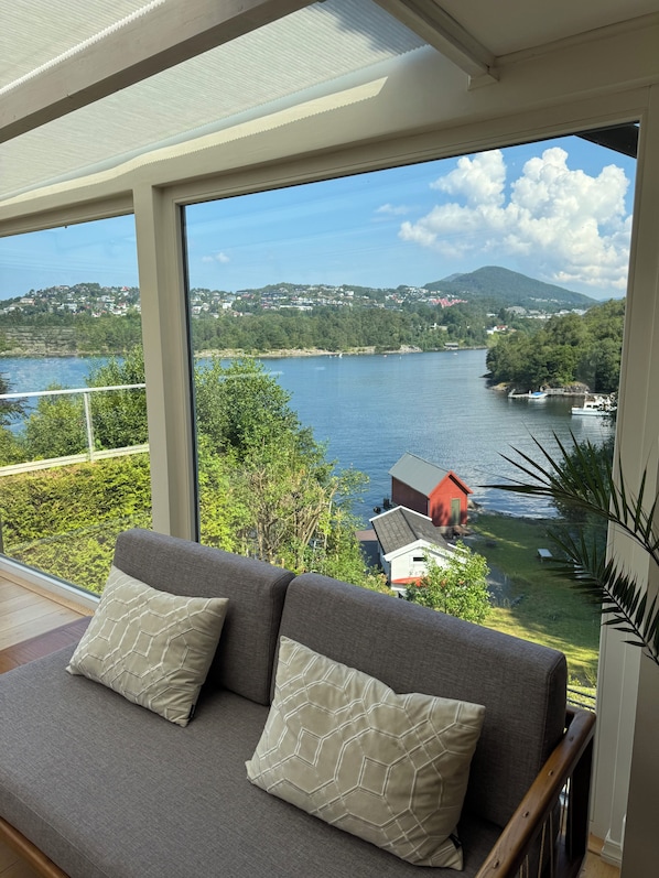 A balcony with a view of a lake, a red building, and a hill in the distance.