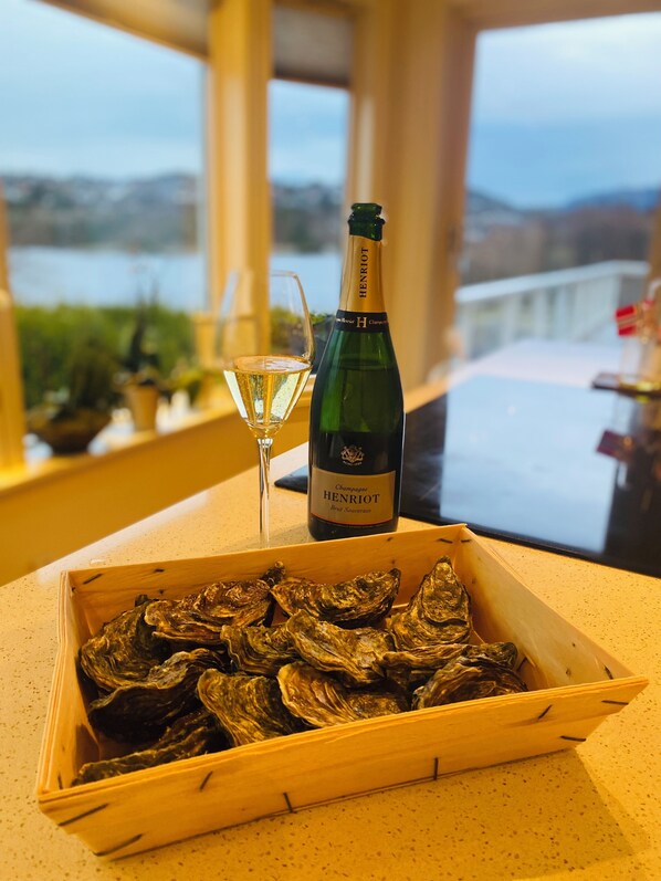 A wooden box of oysters on a table with a bottle of champagne and a glass. - Villa by the sea with access to sea shed and decking (Vestland)