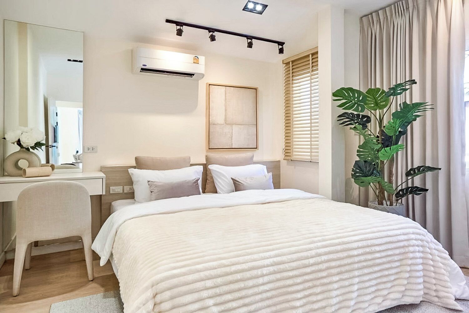 Una habitación de hotel moderna con una cama, un escritorio, un equipo de aire acondicionado, un espejo grande y una planta en maceta.
