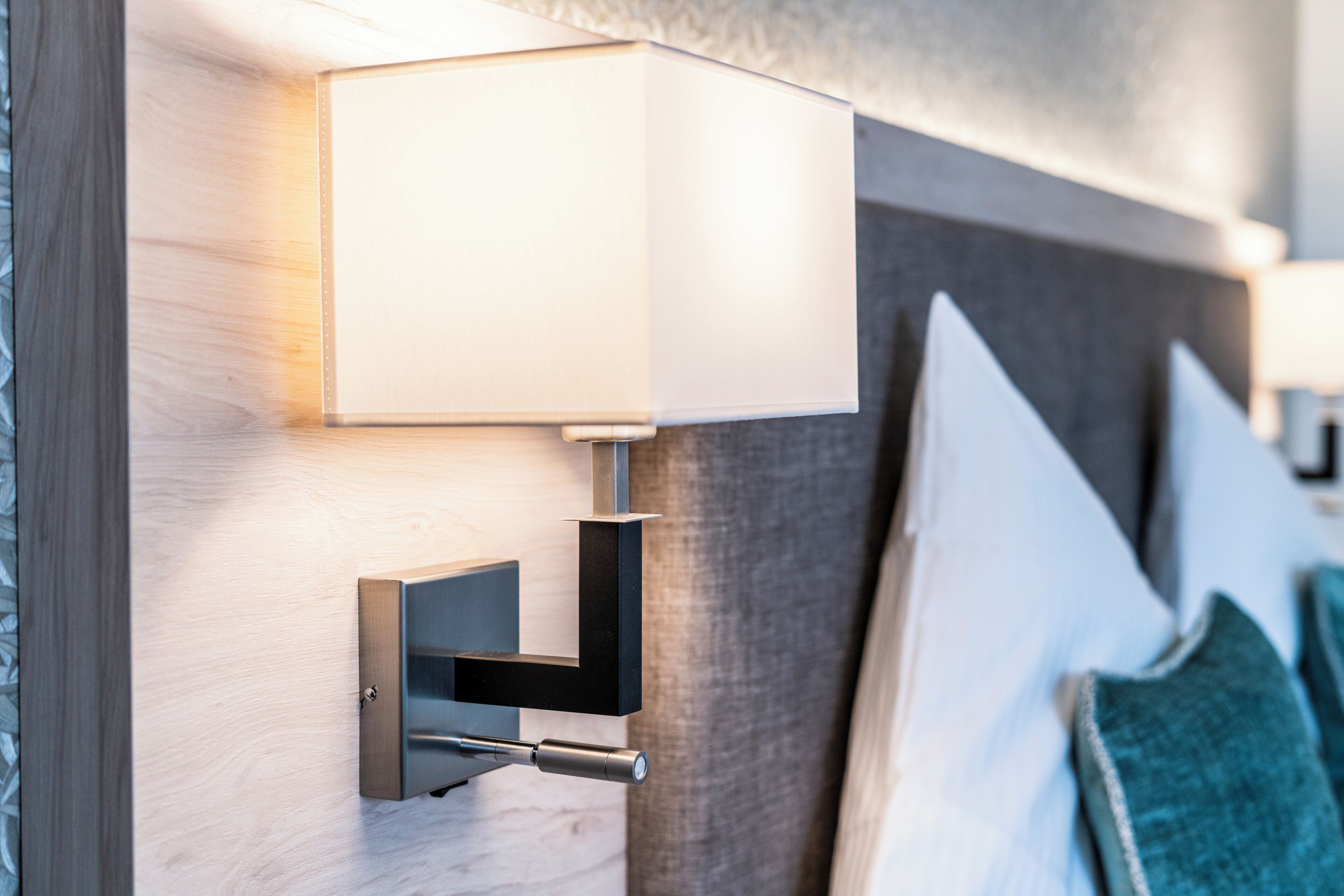 A modern wall-mounted lamp with a rectangular shade, a metallic base, and a visible switch.