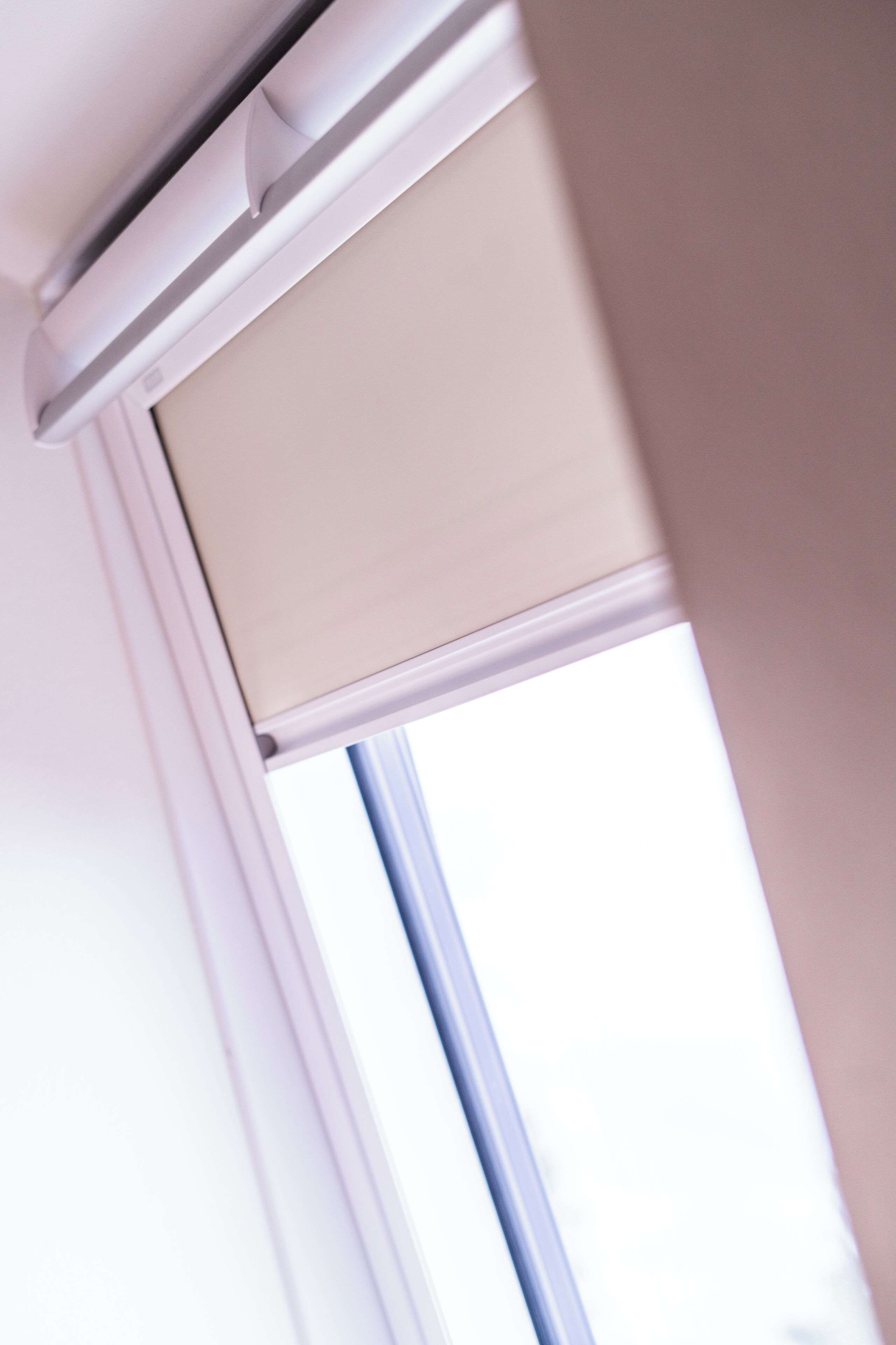 A window with a beige blind partially drawn.