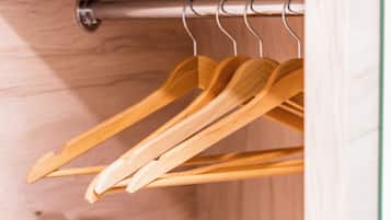 A wooden closet with a metal rod and wooden hangers.