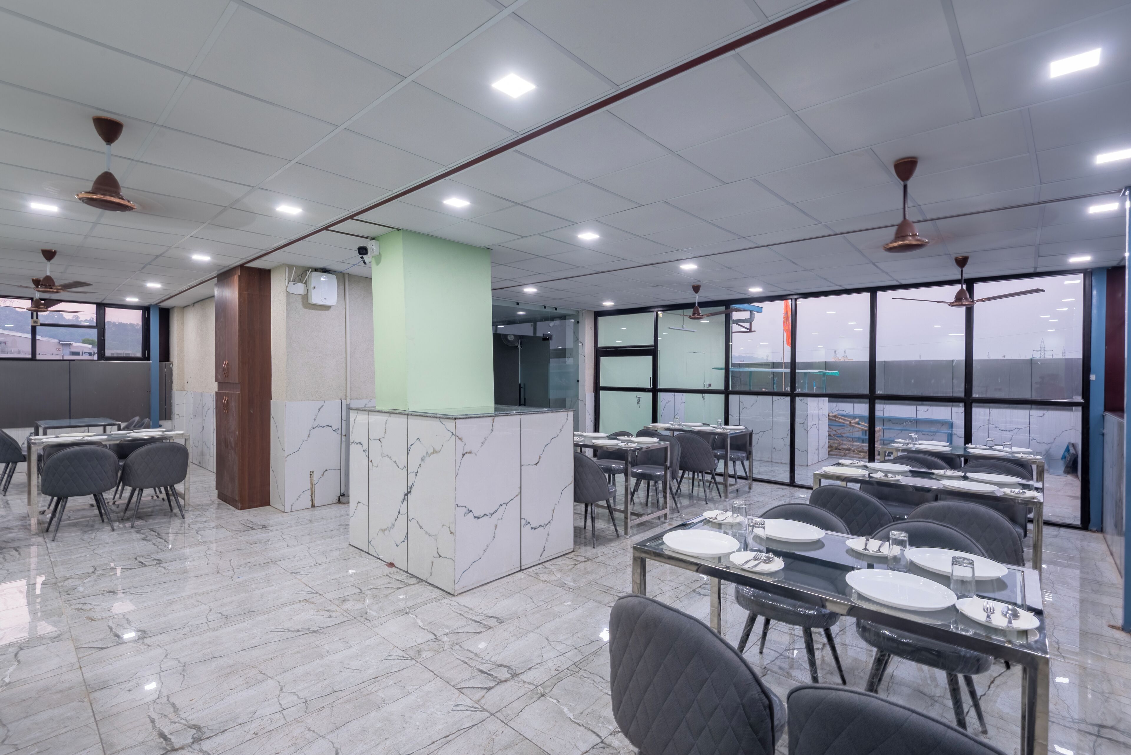 A modern dining area with marble flooring, ceiling fans, and large windows offering a view.