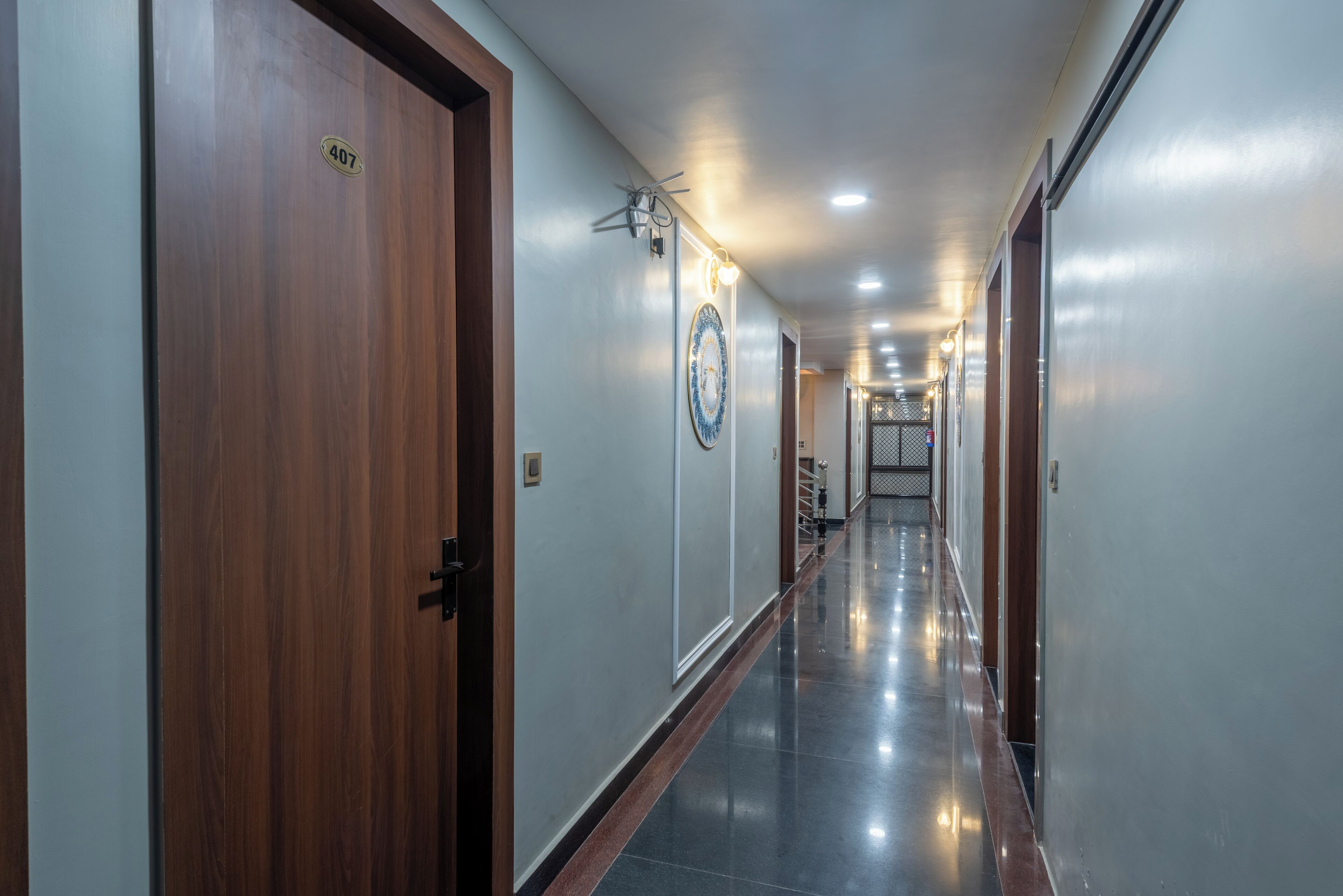 A hallway with wooden doors, a number plate, a decorative plate, and a ceiling light fixture.